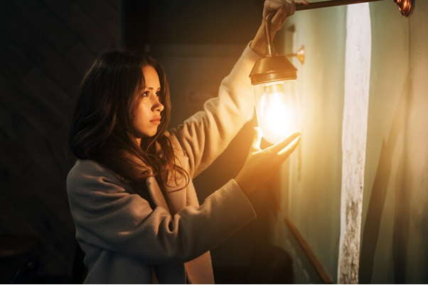 Mulher ajustando uma luminária na parede