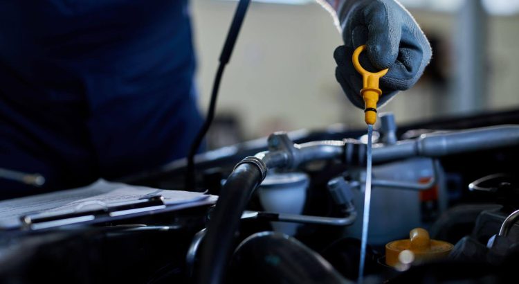Mecânico realizando a troca do óleo do motor do carro.