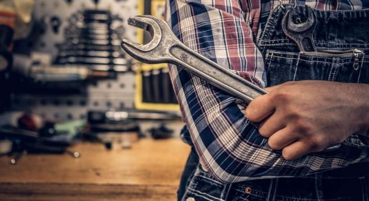 Mecânico usando ferramenta em frente a sua mesa de ferramentas.